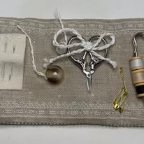 The inside of a miniature travel sewing kit with scissors, pins, needles and threads