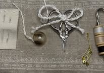 The inside of a miniature travel sewing kit with scissors, pins, needles and threads